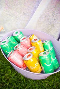 a bucket full of soda cans sitting on the grass