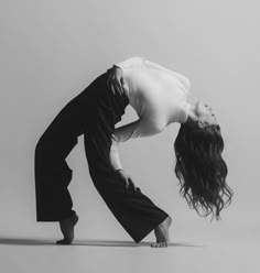 a woman in white shirt and black pants doing a handstand