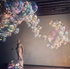 there are many bubbles floating in the air next to a statue and a large wall