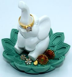 an elephant figurine sitting on top of a green tray with jewelry around it