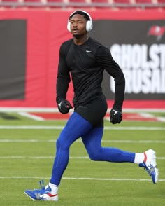 a man wearing headphones and running on a field