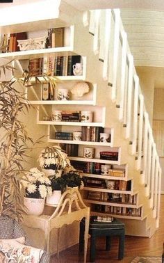 a book shelf filled with books next to a stair case