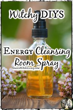 a bottle of energy cleaning room spray sitting on top of a wooden table next to flowers