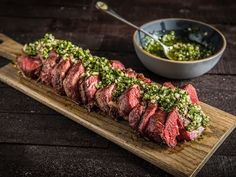 the steak is prepared and ready to be served on the table with sauce in a bowl