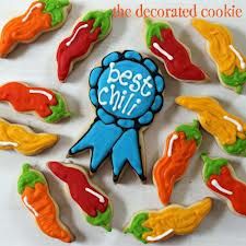 decorated cookies with the words best chili on them in blue and orange icing, surrounded by carrots