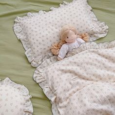 a doll laying on top of a bed next to pillows