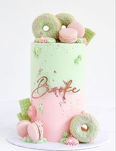 there is a pink and green cake with donuts on the top it says bake