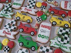 decorated cookies with cars and numbers are on a white tablecloth in the shape of race cars