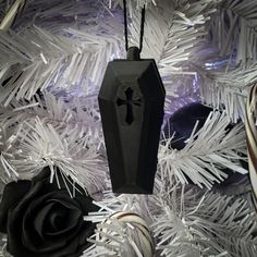 a black ornament hanging from a white christmas tree