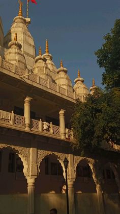 an ornate white building with gold spires and red flag on the roof, under a clear blue sky