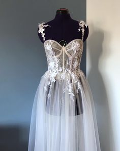 "This wedding corset dress \"Lila\" based on a corset top is made of lace with sequins and soft tulle in different shades. In this bridal dress, the cups are transparent, but it is possible to make them opaque, it is also possible to add a satin skirt so that it is not so transparent, there is a slit in the front. corset and cups are decorated with floral appliqués and shimmering silver beads. The dress has thin straps that are decorated with 3D flowers. If you want to see more variations of wedding dresses, go here: https://www.etsy.com/shop/ANadettaSewing?ref=shop-header-name&listing_id=1324006106§ion_id=39668269 This beach wedding dress will be custom made to your unique measurements and proportionate to your height. After ordering, I will send you a photo with a description of how to t Wedding Corset Dress, Off Shoulder Wedding Gown, Cream Wedding Dresses, Beach Bridal Dresses, Gown Floral, Wedding Corset, Beach Wedding Gown, Bridal Skirts, Transparent Dress