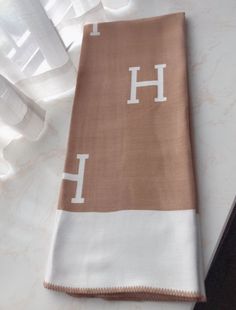 a brown and white towel with the letter h on it sitting on a counter top