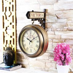 there is a clock on the wall next to a vase with flowers