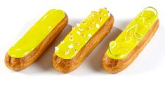 three hotdogs with yellow icing and sprinkles on them sitting next to each other