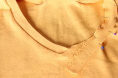 an orange sweater with buttons and sequins on the collar is seen here in close up