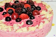 a close up of a cake with berries and almonds on the top, surrounded by other toppings