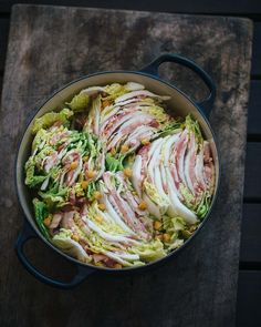 a pot filled with lettuce and meat on top of a wooden table