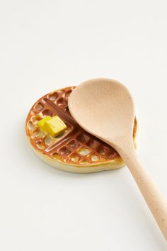 a wooden spoon sitting on top of a waffle covered in butter and syrups