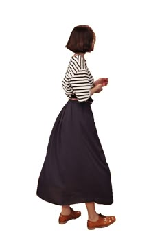 a woman in a striped shirt and black skirt is walking with her hand on her hip