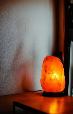 a table with a lamp on top of it next to a mirror and wall in the background