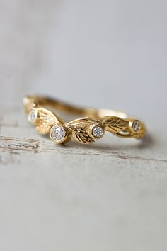 a yellow gold ring with three diamonds on the top and bottom, sitting on a white surface