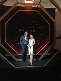 a man and woman standing on stage in front of a large screen with the words bvgaai