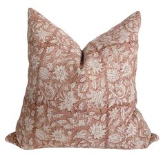 a brown and white floral pillow on a white background