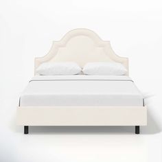 a bed with white linens and pillows on it's headboard is shown