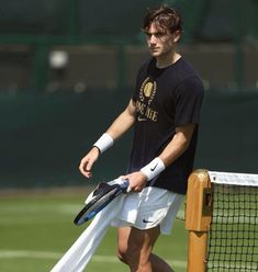 a man holding a tennis racquet on top of a tennis court with a racket in his hand