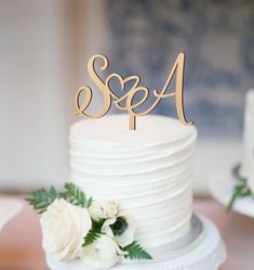 a white wedding cake with two initials on top