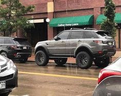 three suvs parked in front of a building on a rainy day with green awning