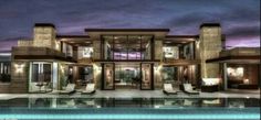 an artist's rendering of a modern house at night with pool and lounge chairs