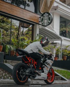 a man riding on the back of a white and red motorcycle in front of a starbucks