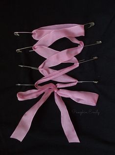 pink ribbon and pins tied together on a black background