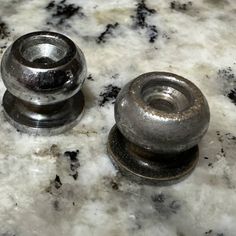 two metal knobs sitting on top of a marble counter