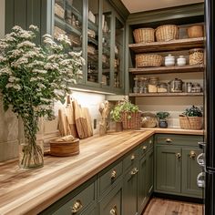 a kitchen filled with lots of green cabinets and wooden counter top next to a plant