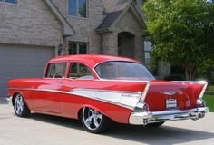 an old red car parked in front of a house