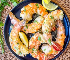 a blue plate topped with cooked shrimp next to lemon wedges and garnished with parsley