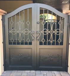 an iron gate with decorative designs on the top and bottom panels, in front of a house