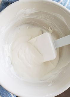 a white bowl filled with cream on top of a blue towel