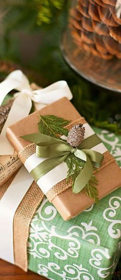 two wrapped presents sitting on top of a table next to pine cones and other decorations