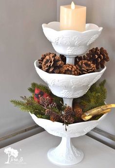 three tiered white dishes with pine cones and candles