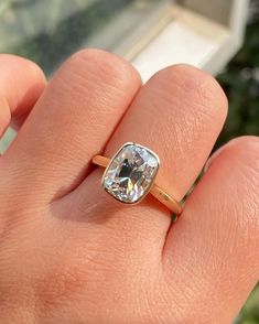 a person's hand holding a ring with a large diamond in the middle of it