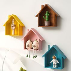 three colorful bird houses on the wall, one with an astronaut figure and another with a cactus