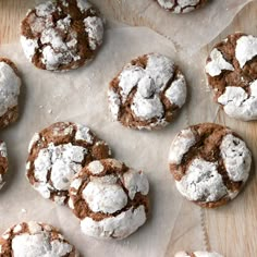 several chocolate crinkle cookies with powdered sugar on top are sitting on a piece of parchment paper