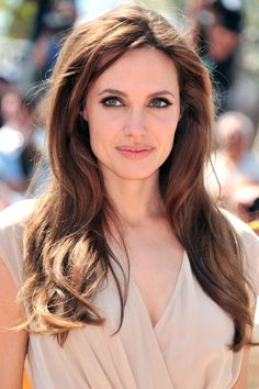 a woman with long brown hair and blue eyes is smiling at the camera while standing in front of a crowd