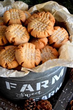 a bucket full of cookies sitting on top of a wooden table next to pine cones