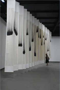 a woman is walking through an art gallery with black and white paintings on the walls