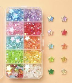 a plastic container filled with lots of different colored beads next to some star shaped magnets