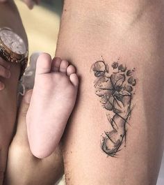 a person with a tattoo on their arm holding a baby's foot and looking at the camera